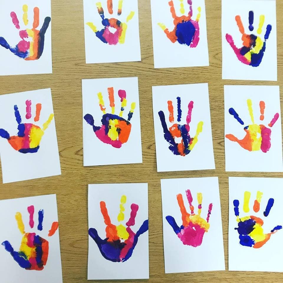 Colorful painted handprints on sheets of paper